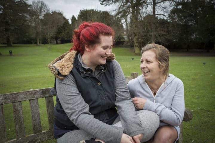 women smiling sitting on a bench