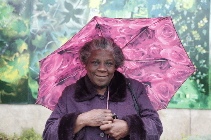 Retired Midwife Joyce Baptise standing by the section of mural she helped to paint outside Newham General Hospital