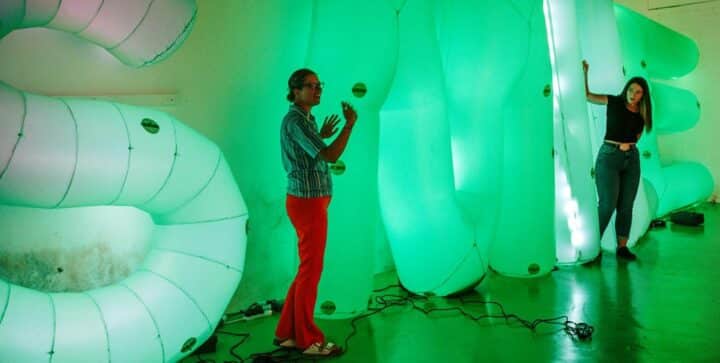 Two women stand infront of sign saying smile