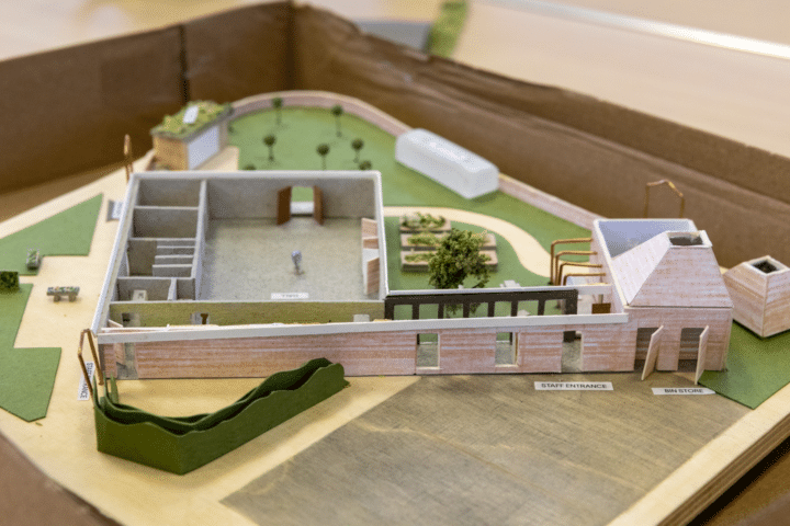 A 3D model of the plans for a community centre, with green space surrounding a community building.
