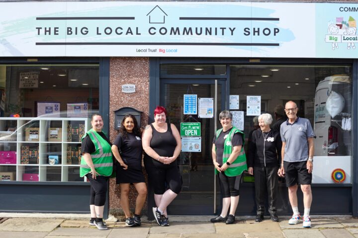 A group of adults standing in front of a shop with a sign above that reads The Big Local community shop.